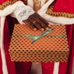 person wearing santa claus outfit while holding christmas gift