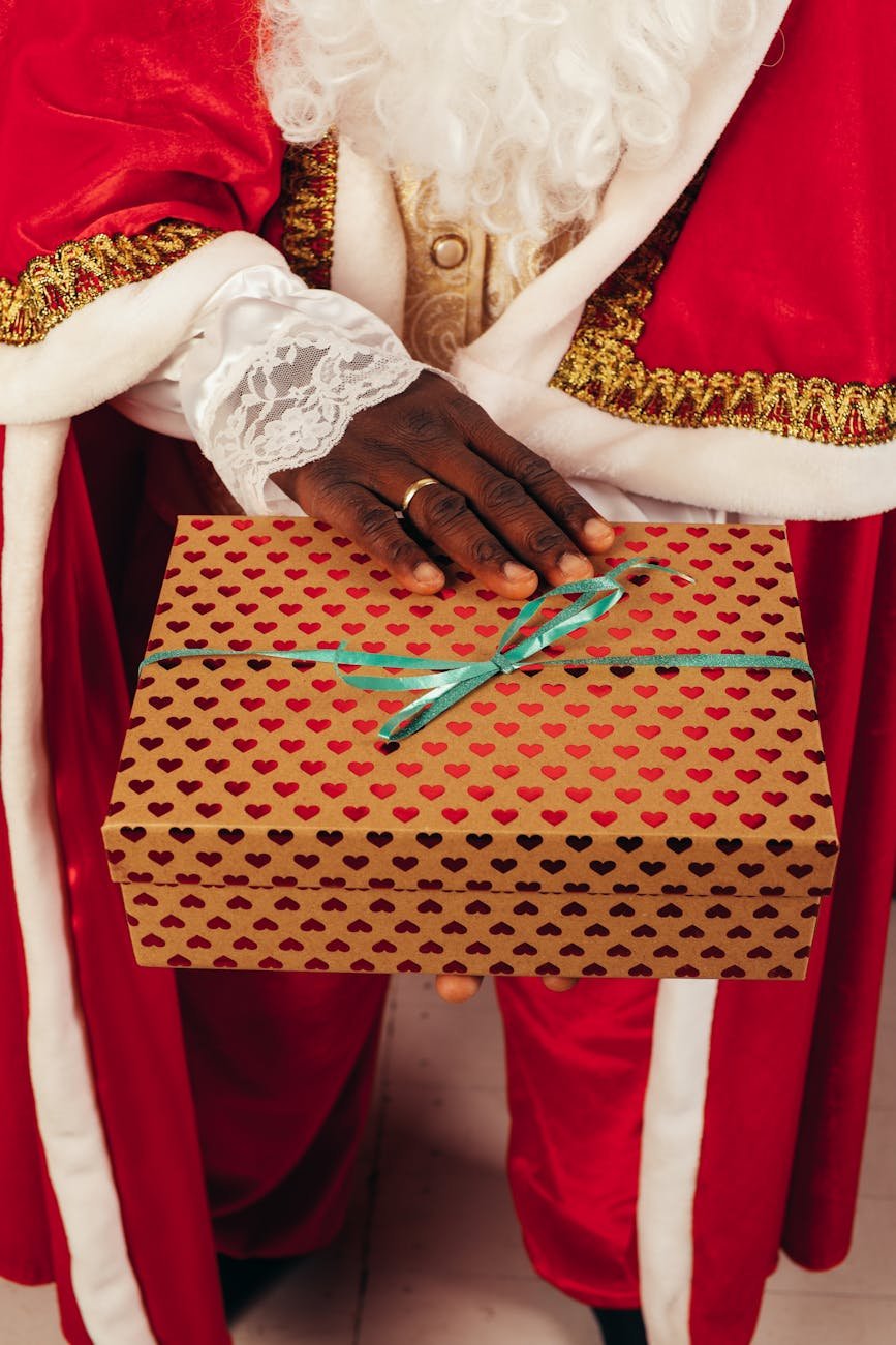 person wearing santa claus outfit while holding christmas gift